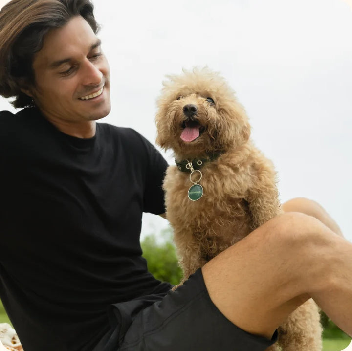 An owner smiling with their dog, back home
