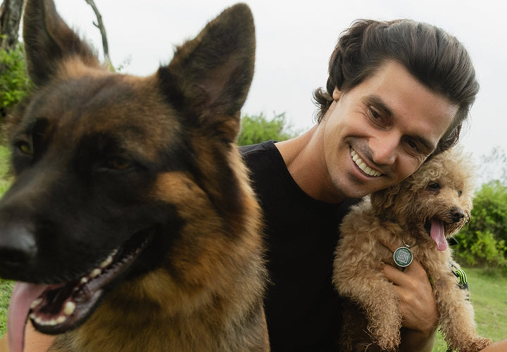 Man with two dogs, one wearing a Supernormal smart tag on its collar