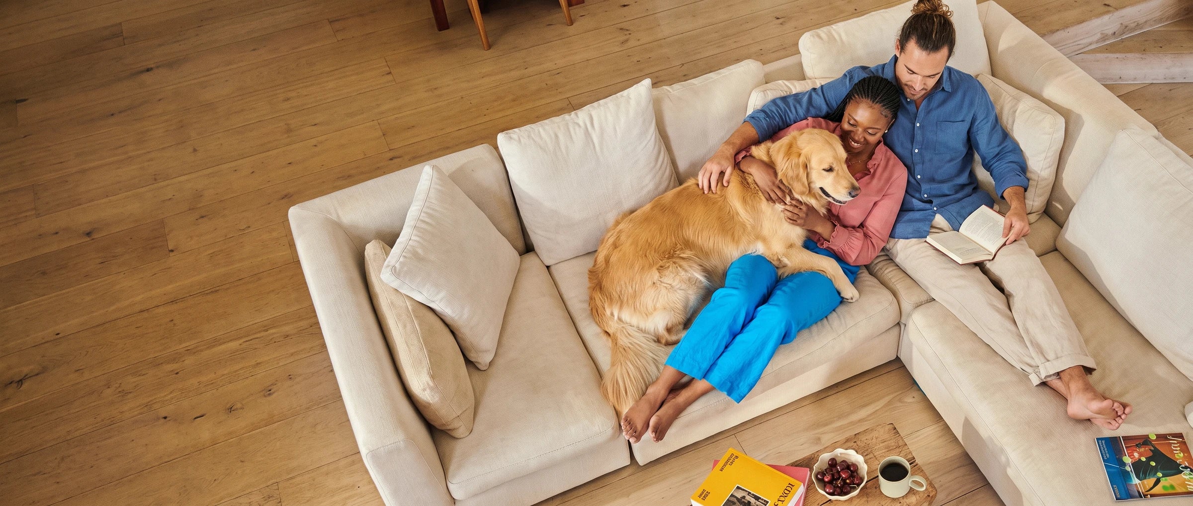 Ein Paar entspannt mit seinem Golden Retriever auf dem Sofa